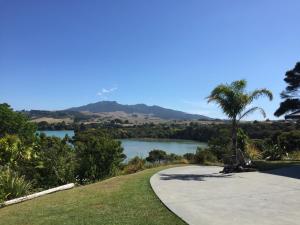 a walkway with a view of a lake and palm tree at STAY WITH US RAGLAN - Studio in Raglan