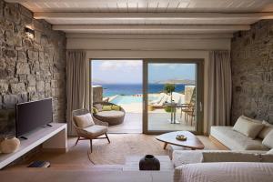 a living room with a couch and a tv and a patio at Hotel Milos Sea Resort in Adamantas