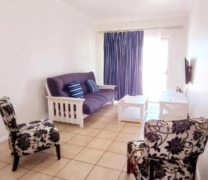 sala de estar con sofá púrpura y 2 sillas en The Sunset Catcher - Langebaan, en Langebaan