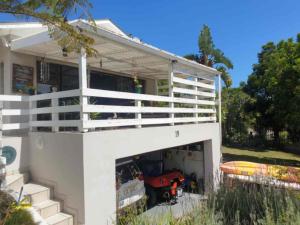 a white house with a garage with a motorcycle in it at Paradise in Plettenberg Bay in Plettenberg Bay