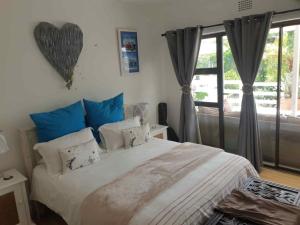 a bedroom with a large bed with blue pillows at Paradise in Plettenberg Bay in Plettenberg Bay