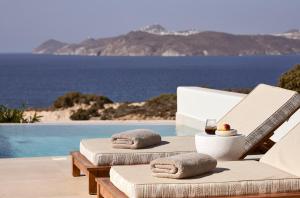 a pool with two chairs and a table with a view of the ocean at Hotel Milos Sea Resort in Adamantas