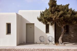 two chairs and a tree in front of a building at Hotel Milos Sea Resort in Adamantas