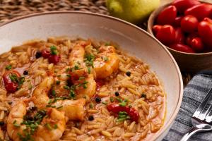a bowl of pasta with shrimp and tomatoes and a bowl of fruit at Hotel Milos Sea Resort in Adamantas