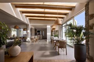a restaurant with tables and chairs and large windows at Hotel Milos Sea Resort in Adamantas