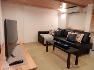 ein Wohnzimmer mit schwarzem Sofa und Fernseher in der Unterkunft Echo Lodge in Kutchan