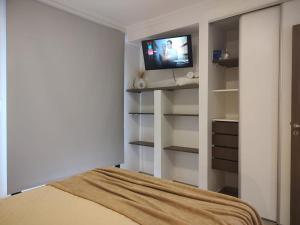 een slaapkamer met een bed en een tv aan de muur bij 3 Personas - Balcon, Wifi & Cafe in Santiago del Estero