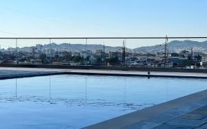 a large swimming pool with a city in the background at Garden Hill Villa Durres in Durrës