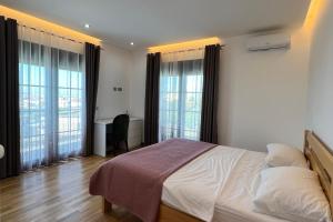 a bedroom with a bed and a desk and windows at Garden Hill Villa Durres in Durrës +20 photos