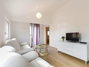 a white living room with a white couch and a tv at Villa Patricia in Štinjan