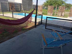 eine Hängematte und zwei Stühle neben einem Pool in der Unterkunft CASA quinta ""LUZ AZUL"" con pileta, galeria, calefaccion , doble aire frío calor, WIFI in Santa Rosa + 9 Fotos