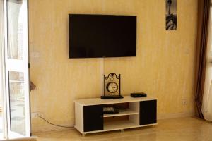 een woonkamer met een tv aan een muur met een klok bij Dar Othmen in Tozeur