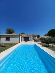 a blue swimming pool in front of a house at Villa avec piscine in Gaujac