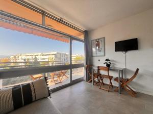 a living room with a table and a large window at Heliotel Marine Studio 30m2 très lumineux avec terrasse 17m2 au 3eme étage in Saint-Laurent-du-Var