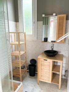 ein Badezimmer mit Waschbecken und Spiegel in der Unterkunft La Petite Maison in Murat-le-Quaire