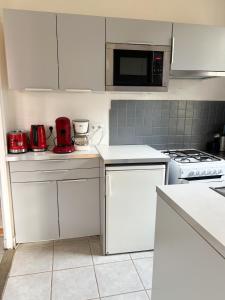 eine Küche mit weißen Schränken und einem roten Gerät in der Unterkunft La Petite Maison in Murat-le-Quaire + 2 Fotos