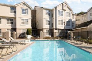 a swimming pool with chairs and a building at Residence Inn Pleasanton in Pleasanton