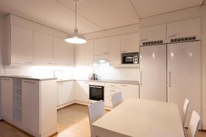 a white kitchen with a table and a white refrigerator at Transit Rooms & Sauna Airport Hostel in Vantaa