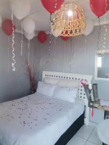 a bedroom with red and white balloons and a bed at Oceans Black in Durban