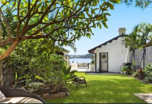 a yard with a white house and a bench at Sydney Harbourfront Boathouse and Studio Escape in Sydney