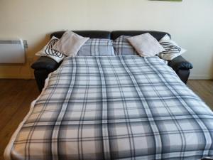 a bed with a plaid blanket on top of it at Coasters Holiday Flats in Macduff