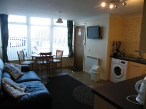 a living room with a couch and a kitchen with a table at Coasters Holiday Flats in Macduff