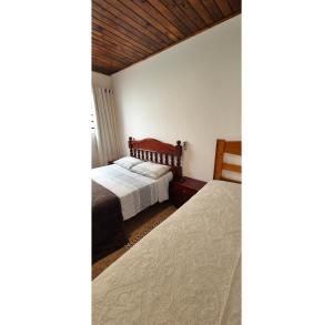 a bedroom with two beds and a wooden ceiling at Kitnet perto da rodoviária Campos do Jordão in Campos do Jordão