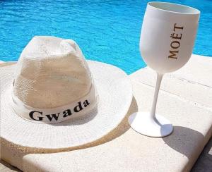 a hat and a straw wine glass next to a pool at Villa du bonheur in Goyave