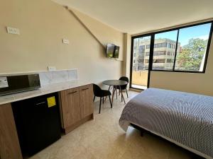 a room with a bed and a kitchen with a microwave at Suitesecu Rentals Cuenca in Cuenca