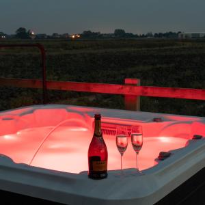 a bottle of wine and two wine glasses in a hot tub at Holly Lodge - Quirky Shepherd's Hut With Hot Tub - Bespoke Made From A Salvaged Railway Carriage in Boston +5 photos