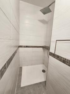 a white bathroom with a shower with a drain at T2 Moderne Centre Ville in Le Havre