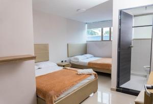 ein Schlafzimmer mit zwei Betten und einer Dusche in der Unterkunft HOTEL DASANTO HD in Barranquilla