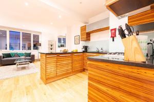 a kitchen with wooden cabinets and a living room at Bright & Modern One Bedroom Flat in Farringdon in London