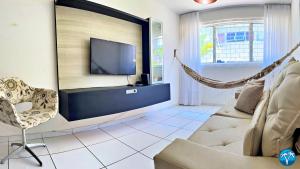 a living room with a couch and a tv and a hammock at Vacanze - Jardim Tropical in Maceió