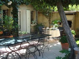 d'une terrasse avec une table et des chaises sous un arbre. dans l'établissement Arles les Alyscamps, à Arles