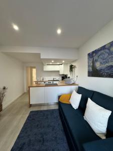 a living room with a blue couch and a kitchen at Apartamento em Cascais in Cascais +12 photos