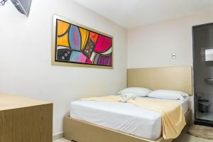 ein Schlafzimmer mit einem Bett und einem Gemälde an der Wand in der Unterkunft HOTEL DASANTO HD in Barranquilla