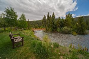 a bench sitting in the grass next to a river at Snowdance B102 by SummitCove Lodging in Keystone
