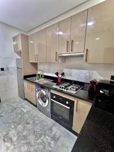 une cuisine avec une cuisinière et une machine à laver dans l'établissement Liliapart, à Agadir