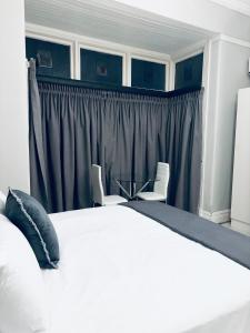 a bedroom with a white bed and two chairs at Stay-Tiah Whyte Room in Durban