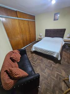 a bedroom with a bed and a leather couch at En la cañada cerca de todo in Córdoba