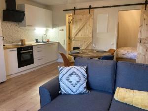 a living room with a blue couch and a kitchen at Le renard roux in Vresse-sur-Semois