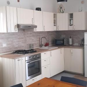una cucina con mobili bianchi e un forno a piano cottura di La comodità a due passi dal mare di Mondello a Mondello Altre 37 foto