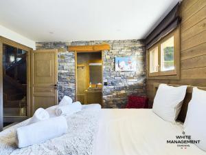 a bedroom with a large bed and a stone wall at Chalets Le Cepe - Chalet familial moderne à Courchevel Moriond MAE-1951 in Courchevel