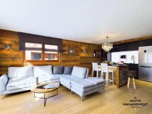 a living room with a couch and a kitchen at Chalets Le Cepe - Chalet familial moderne à Courchevel Moriond MAE-1951 in Courchevel