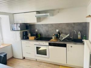 a kitchen with white cabinets and a stove top oven at gîte du château in Lutzelbourg