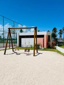 a swing set in a playground in front of a building at Aláfia Porto de galinhas Mana beach in Porto De Galinhas