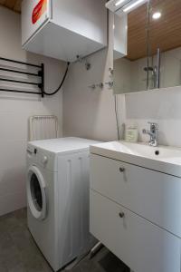 a white laundry room with a sink and a washing machine at Easy Stay Rooms & Apartments near Airport in Vantaa