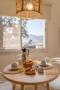 a wooden table with breakfast foods on it in front of a window at Samai Suma Cabañas & Spa in Villa General Belgrano