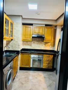a kitchen with wooden cabinets and a sink and a dishwasher at Marina Panorama Apartement in Agadir